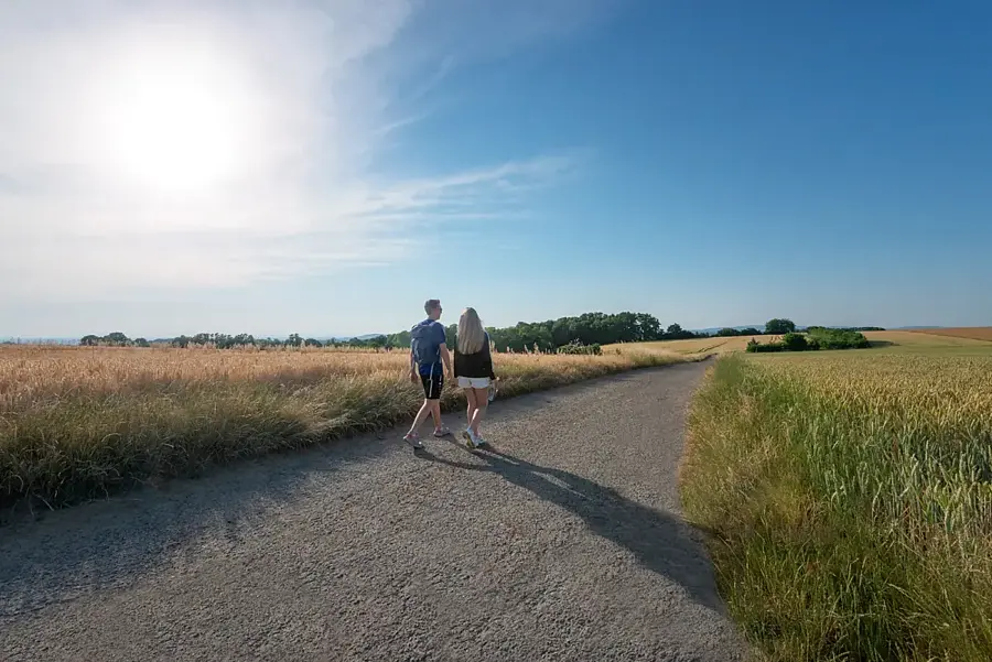 Feldweg zwischen Getreidefeldern im Kraichgau – zwei Spaziergänger unter weitem Himmel