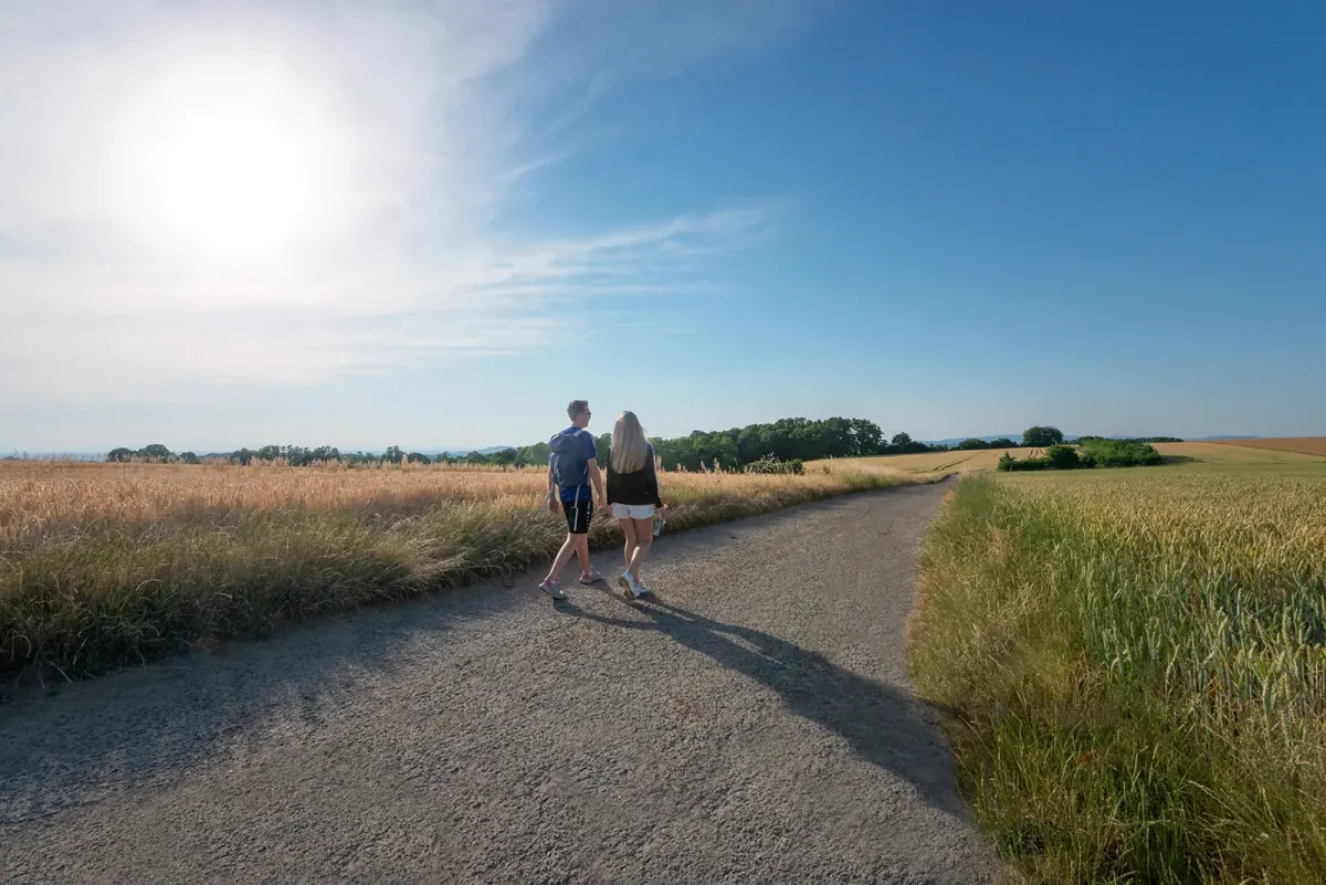 Feldweg zwischen Getreidefeldern im Kraichgau – zwei Spaziergänger unter weitem Himmel